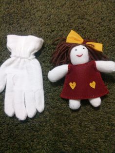 two knitted dolls are laying on the floor next to each other, one is wearing a red dress and white gloves