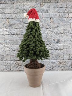 a small christmas tree in a pot with a santa hat on it's head