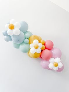 balloons are arranged in the shape of flowers on a white surface with one balloon attached to it's side