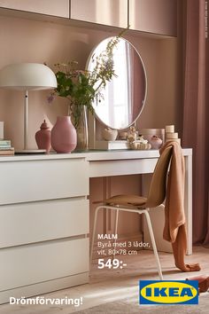 a dresser with a mirror, lamp and vase on it