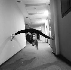 a woman doing a handstand on the floor in an office building with her legs spread out