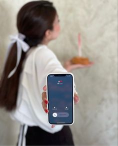 a woman holding an iphone in her hand and looking at the food on the plate