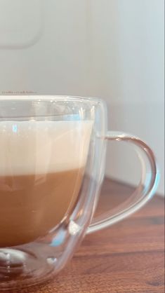 a glass cup filled with liquid sitting on top of a wooden table