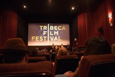 people sitting in chairs watching a movie on a screen at the tribeca film festival