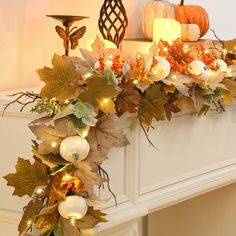 a decorated mantle with candles and pumpkins