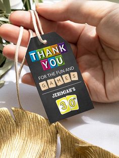 a hand holding a thank you for the fun and game's 30th birthday tag