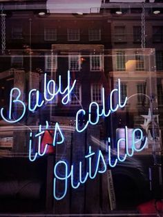 a neon sign that says baby it's cold outside in front of a window