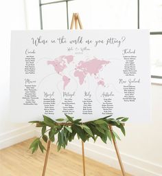 a wedding seating chart on a easel in front of a window with greenery