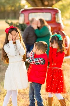 three children are standing in front of an old truck with their hands on their faces