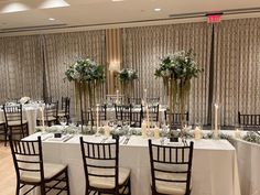 the tables are set up with white linens and centerpieces in vases