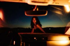 a woman is sitting in the back seat of a car at night with her headlight on