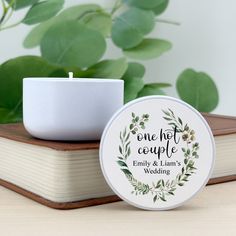 a candle sitting on top of a book next to a cup and planter with greenery