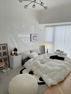 a large white bed sitting inside of a bedroom on top of a hard wood floor