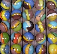 a box filled with lots of colorful marbles on top of a table next to each other