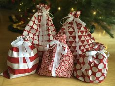 three bags with white and red designs on them sitting next to a christmas tree