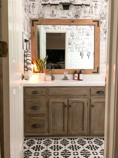 a bathroom with black and white wallpaper and wooden vanity, large mirror above the sink