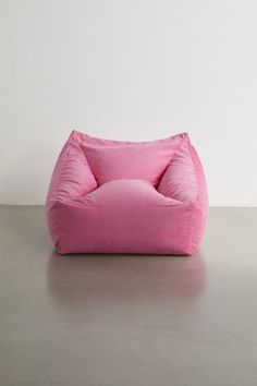 a pink bean bag chair sitting on top of a cement floor next to a white wall