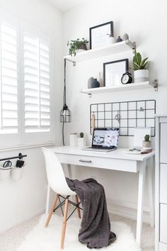 a white desk with a laptop computer on top of it next to a shelf filled with potted plants