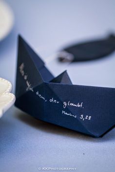 an origami boat with writing on it sitting next to a plate and fork