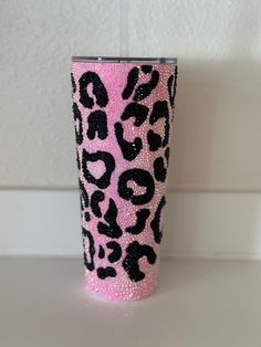 a pink and black leopard print cup sitting on top of a white counter next to a wall