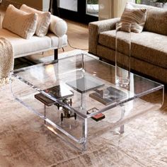 a glass coffee table sitting on top of a rug in a living room next to a couch