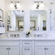 a white bathroom with double sinks and mirrors