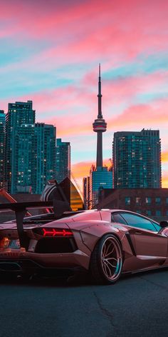 a very nice looking car parked in front of some tall buildings with the sky in the background