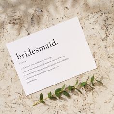 a piece of paper with the words bridesmaid written on it next to a plant