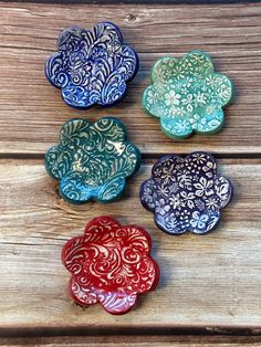 four decorative plates sitting on top of a wooden table