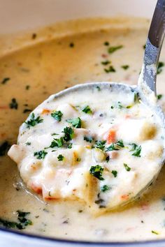 a ladle full of soup with broccoli and cheese in it is being held by a spoon