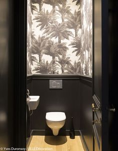 the bathroom is decorated in black and white with palm trees on the wall behind the toilet