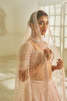 This lehenga set features tonal embroidery in delicate sequin and crystal. The blouse has a plunging neckline with crystal pieces at the center. The elbow sleeves has exaggerated tassels. The four sided embroidered dupatta has an all over jaal as well. The outfit has pink crystal drops.From Seema Gujral's Inara collection. DELIVERY TIMEPlease allow 8-12 weeks for your outfit to arrive. FABRIC DETAILSLehenga - organza, Bluose- Net, Dupatta - net Professional cleaning only. Glamorous Sequined Choli For Eid, Glamorous Embellished Lehenga For Eid, Glamorous Embellished Dupatta For Eid, Glamorous Embellished Choli For Eid, Glamorous Diwali Lehenga With Sheer Dupatta, Glamorous Diwali Choli With Sheer Dupatta, Glamorous Dupatta For Eid Reception, Diwali Glamorous Choli With Sheer Dupatta, Glamorous Choli With Dupatta For Eid