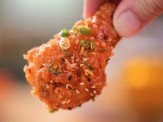 a hand holding up a piece of food with seeds and seasoning on it's surface