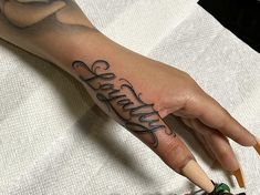 a person's hand with the word faith tattooed on it, holding a pencil