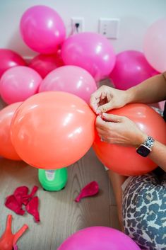 a woman sitting on the floor with pink and orange balloons