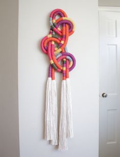 a colorful wall hanging with tassels on it's sides and a door in the background