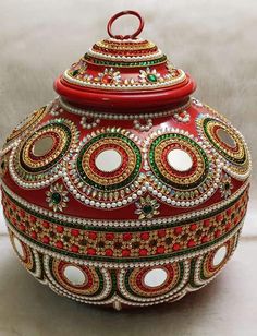 a red and gold decorated vase sitting on top of a table