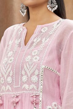 Pink mulmul chanderi kurta with white thread embroidery, embellishment of mirrors, shells, handmade tassels and side slits. Paired with a cotton embroidered Pakistani salwar, lehriya crinkled dupatta and sleeveless slip.
Component: 4
Pattern: Embellishment and Embroidered
Type Of Work: Mirror and Thread Work
Neckline: Notched Round Neck
Sleeve Type: Batwing Sleeves
Fabric: Kurta: Mulmul Chanderi, Cotton
Color: Pink
Other Details: 
Tassels details on kurta)
Gota work stripes on dupatta
Pom-Poms t Mulmul Kurta, Cotton Thread Embroidery, Pink Kurta, Trendy Outfits Indian, Emb Designs, Pakistani Salwar, Hand Embroidery Dress, Gota Work, Embroidery On Kurtis