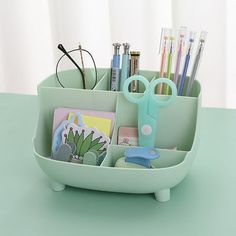 a cup with pens, pencils, scissors and other items in it on a table