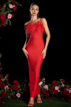 a woman in a red dress posing for the camera with flowers around her and a black background