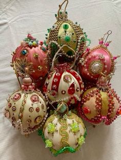 a bunch of ornaments that are sitting on a white table cloth, all in different colors and sizes