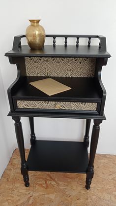 an ornate black and gold side table with a vase on top