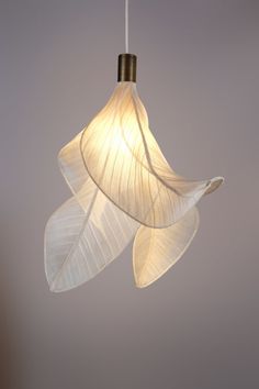 a white light hanging from a ceiling with two leaves attached to the lightshade