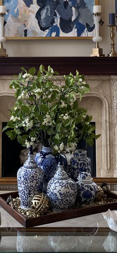 blue and white vases are sitting on a tray in front of a fireplace mantel