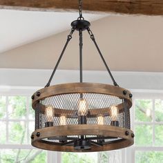 a wooden chandelier hanging from the ceiling in a room with white walls and windows