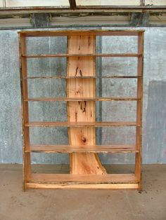 a book shelf made out of wooden planks in front of a concrete wall and cement floor