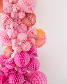 a bunch of pink honeycombs hanging from the ceiling in front of a white wall