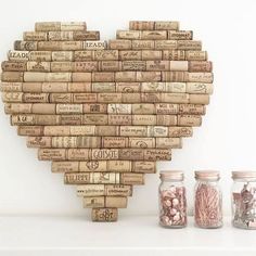 a heart made out of wine corks on a white surface next to two jars