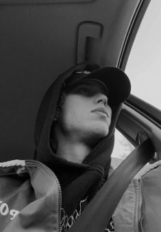 a man sitting in the back seat of a car wearing a hoodie and looking out the window