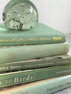 a stack of books sitting on top of each other next to a glass ball with water droplets